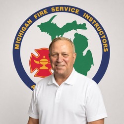 Smiling man in a white polo shirt stands in front of the Michigan Fire Service Instructors emblem.