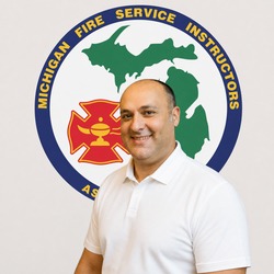Man in white polo standing in front of the Michigan Fire Service Instructors Association logo.