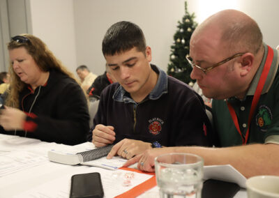 People seated at a table examining documents, with a spiral notebook and a smartphone in the foreground.